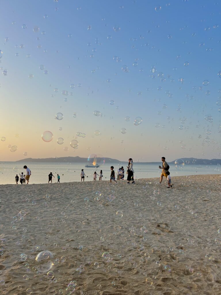 Sunset at Fusaki Beach with silhouettes of people and bubbles
